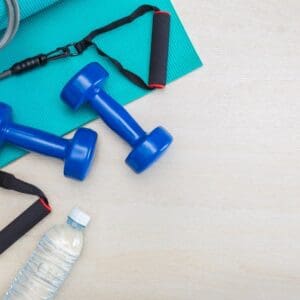A table with two blue dumbbells and water bottle.