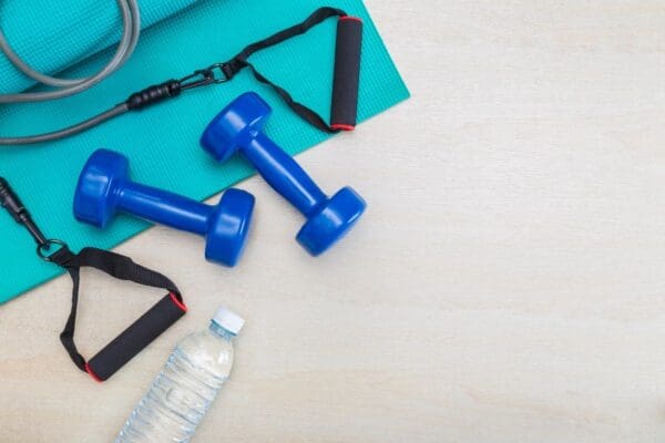 A table with two blue dumbbells and water bottle.