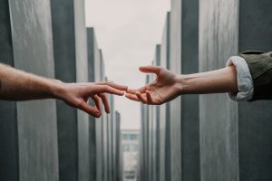 Two hands reaching out to each other in a line of concrete buildings.