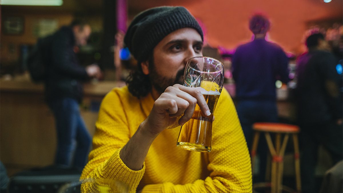 France, Paris, Close-up of man holding a beer inside a bar.