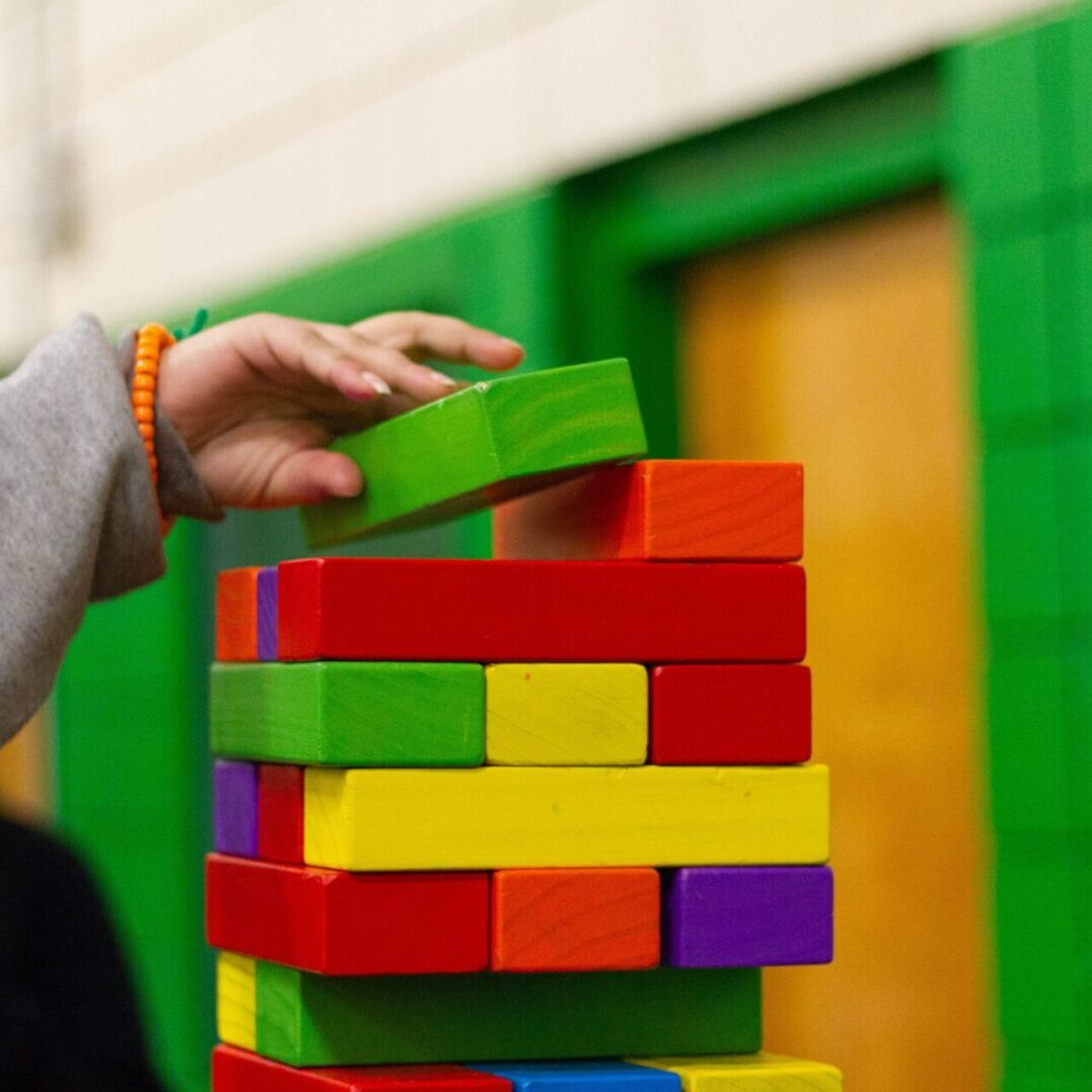 A person playing with blocks in front of a green wall.